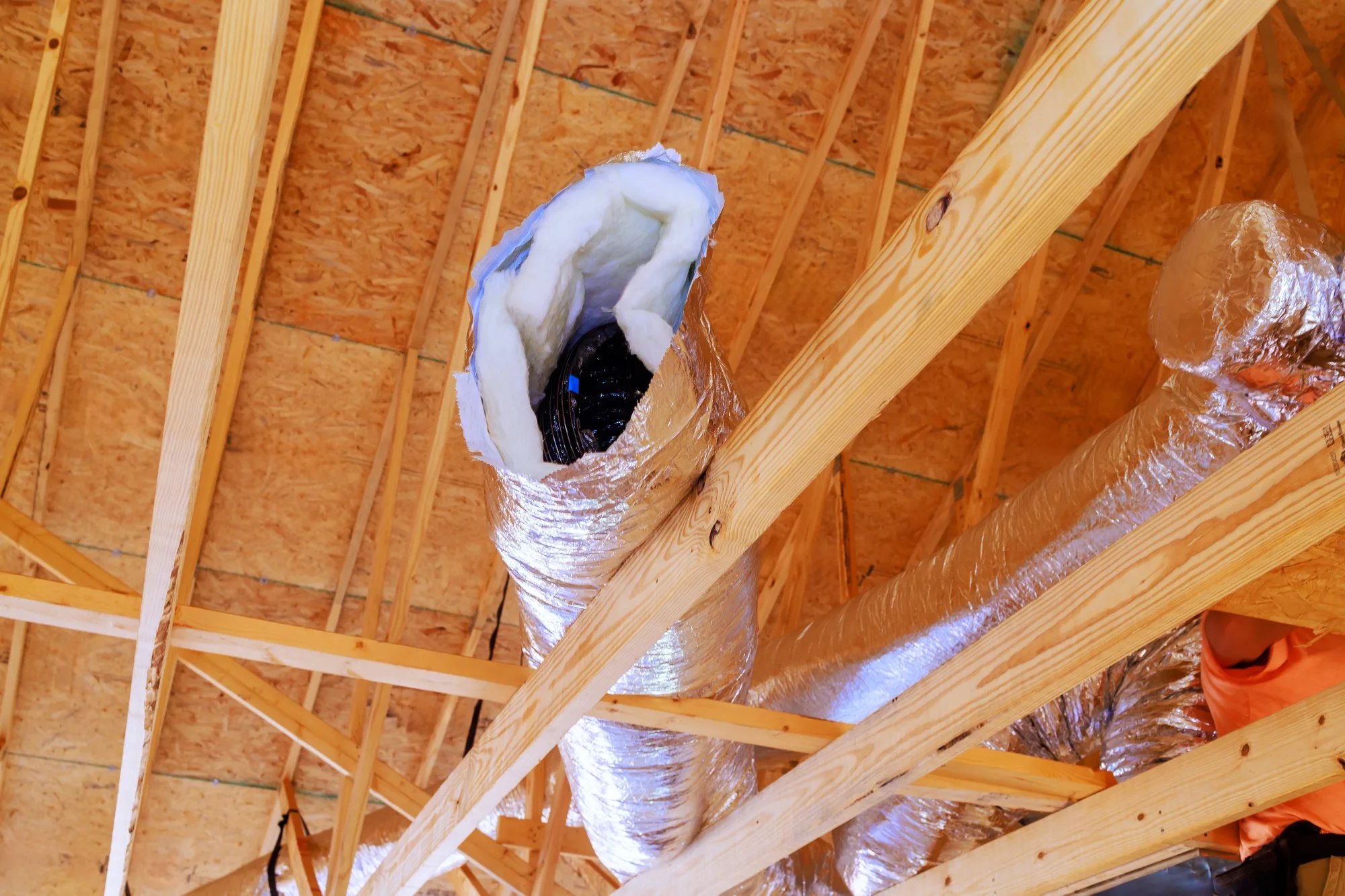 In construction of home, silver insulation ventilation HVAC pipes were installed from ceiling to a