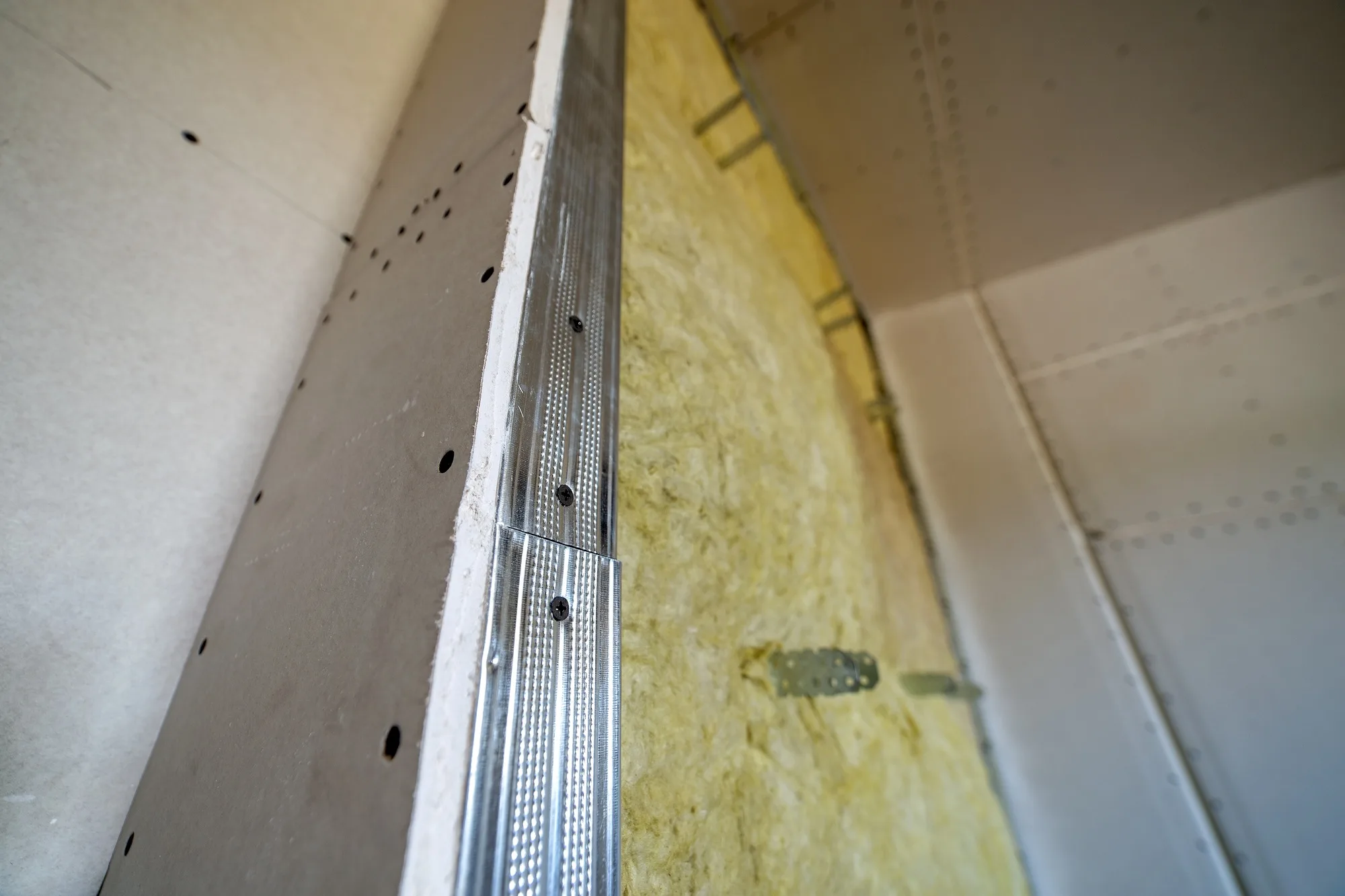 Wall of a room under renovation with mineral rock wool insulation and metal frame prepared for